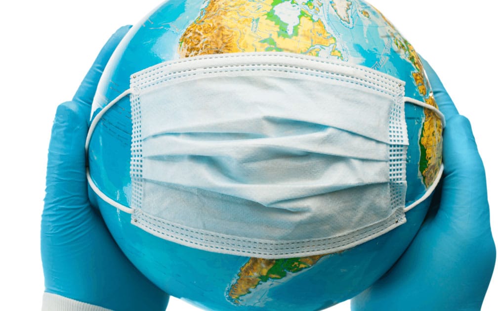 A globe with a surgical mask stretched across it by latex-gloved hands to illustrate global pandemic threats