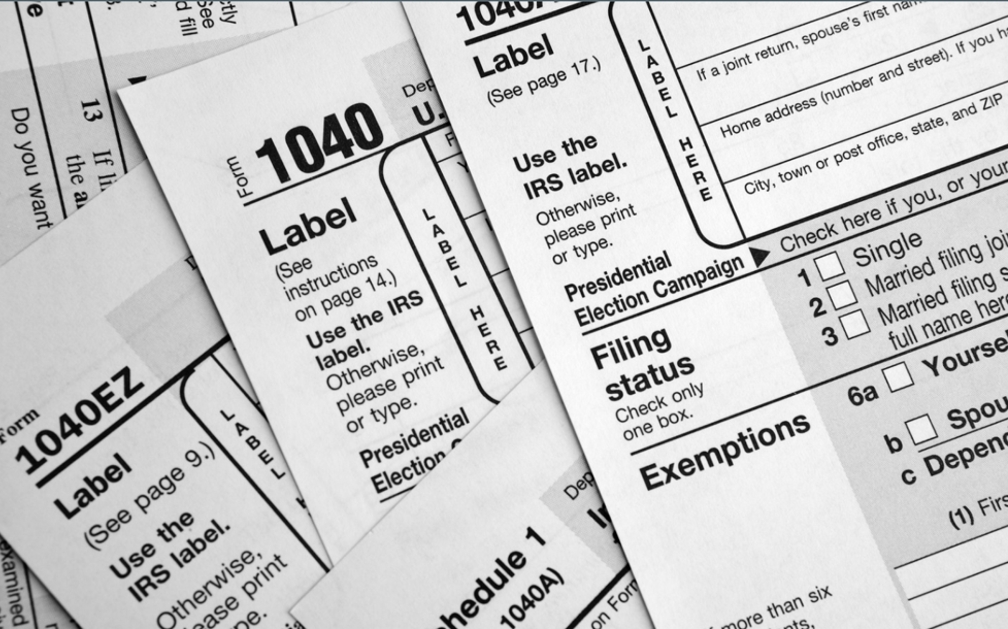 The image is full of various tax forms to illustrate the concept that taxes can have an impact on life insurance purchases.