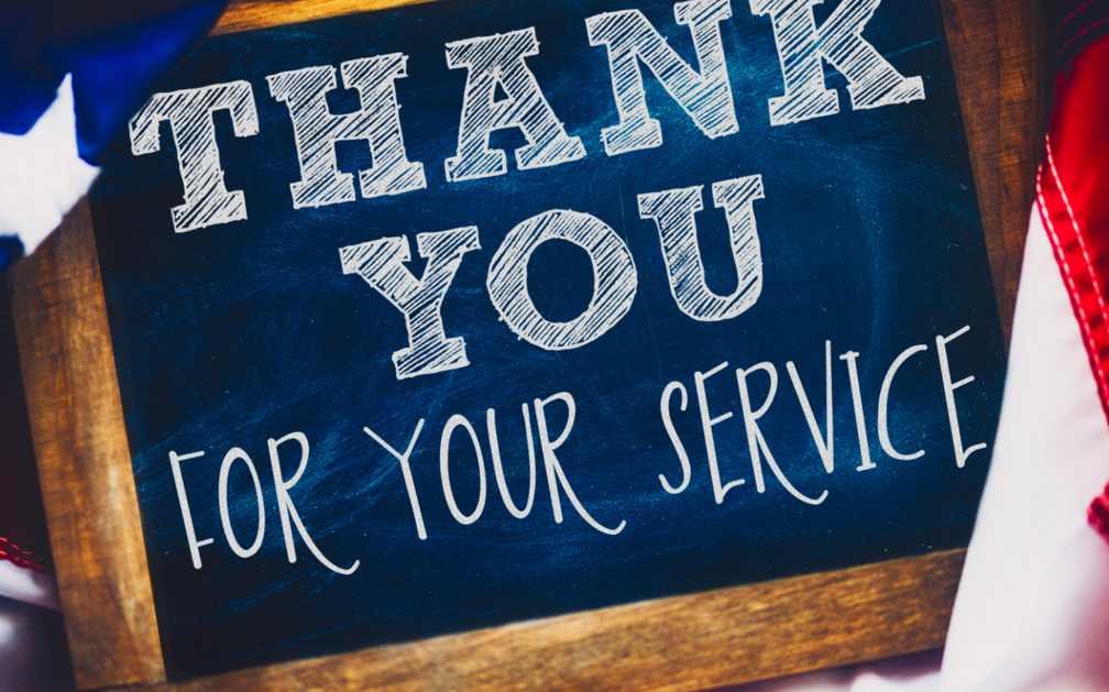 A sign on a wood background reads, “THANK YOU FOR YOUR SERVICE”. The image accompanies a blog post about term life insurance for military veterans.